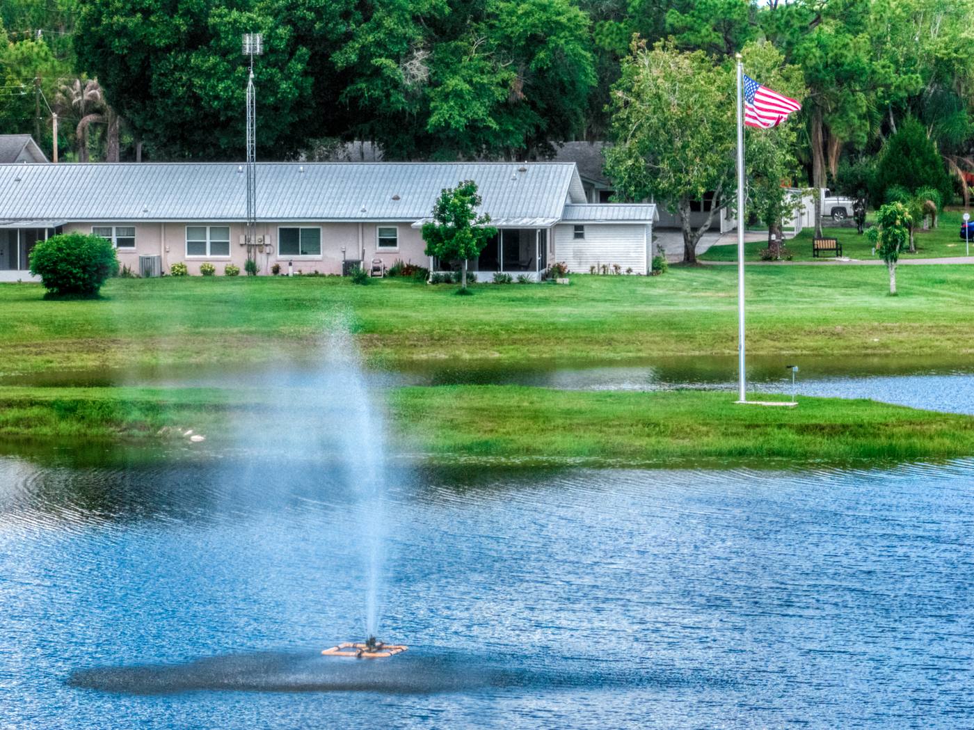 The lake fountain with the flag and a row of apartments behind